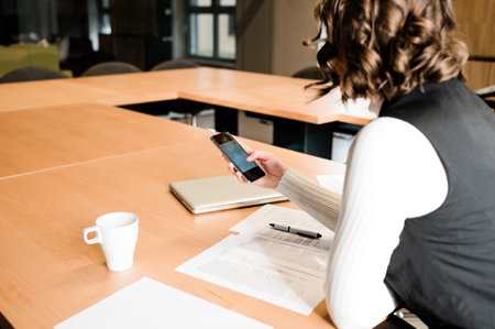 Woman in the office scroll on her smartphone during the lunch brake. Everyday technology in the business concept.の写真素材