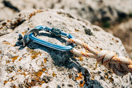 Close Up of climbing gear, Anchor, Rope, and Carabiner with cliff rock as a backdrop.の写真素材