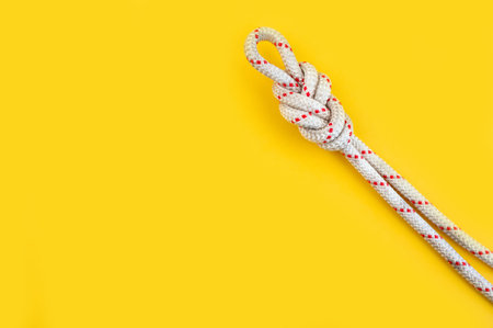 Rope with the Knot eight. Isolated on the yellow background. Minimal concept, copy space.