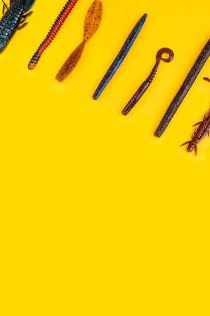 Bass fishing concept on the yellow trendy background. Flat lay style. Fishing tackle, soft silicon lures, spinner bait and wobblers.の写真素材
