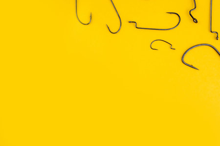 Fishing hooks on the trendy yellow backdrop. Flat lay, copy space. Fishing concept with worm hook.