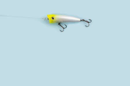 Bass fishing concept on the blue trendy background. Flat lay style. Fishing tackle, popper lure on the line.の写真素材