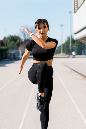 Young woman doing fitness outdoors and walking high knees exercise. Sunny summer day training.
