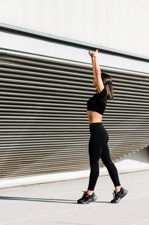 Fit girl in the black fitness outfit posing for a photo. Isolated in the front of the blown out...
