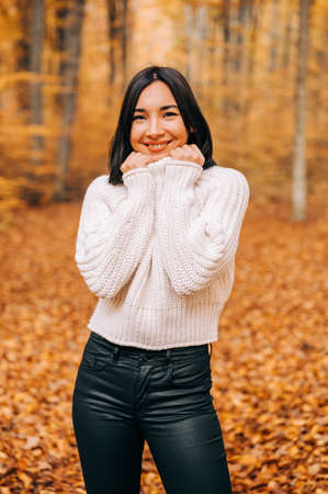 Portrait of young woman in the woods during the colourful fall season. happy girl posing in the forest.の写真素材