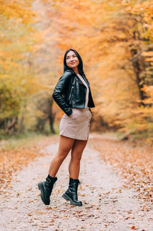 Portrait of young woman in the woods during the colourful fall season. happy girl posing in the forest.の写真素材