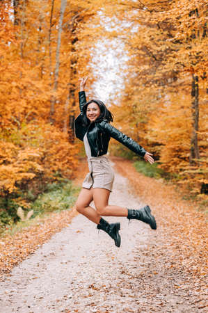 Portrait of young woman in the woods during the colourful fall season. happy girl posing in the forest.の写真素材