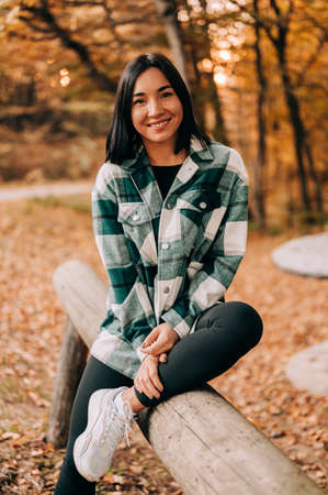 Portrait of young woman in the woods during the colourful fall season. happy girl posing in the forest.の写真素材