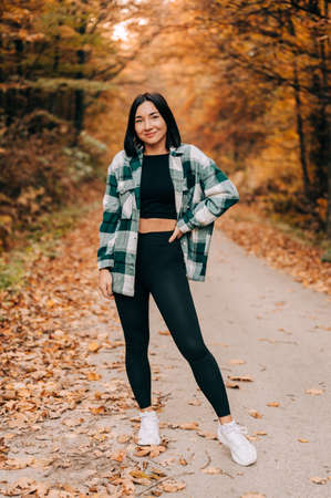 Portrait of young woman in the woods during the colourful fall season. happy girl posing in the forest.の写真素材
