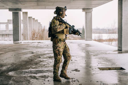 Special forces operator wearing Multicam uniform and his assault rifle HK 416 while practicing CQB combat training in the abandoned building. Coyote brown and mc gear in the urban environment.の写真素材