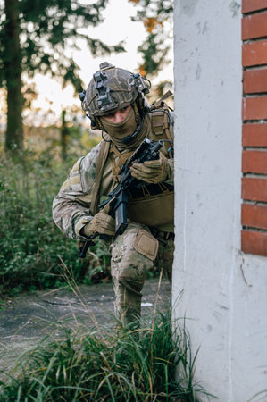 Soldier with assault rifle standing near wall and looking at cameraの写真素材