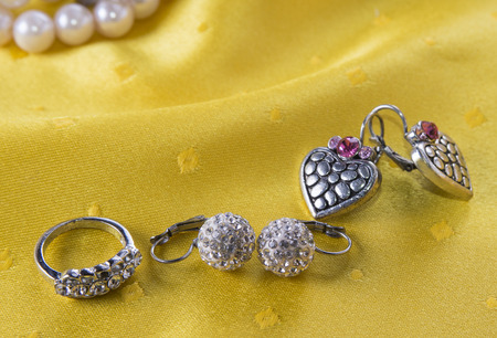 Two pairs of earings and ring on the yellow backgroundの写真素材