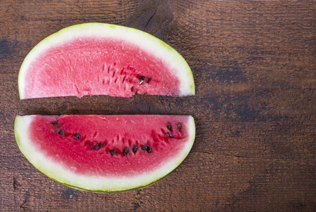 Two watermelon slices on the wooden board opposite each otherの写真素材