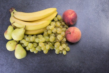 Top of kitchen table is full of fruit grapes, bananas, pears, peachesの写真素材