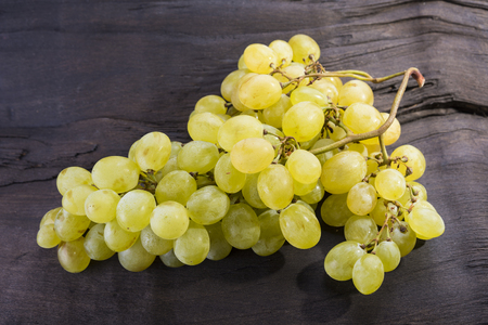 Yellow friut grapes is sitting on the dark woodの写真素材