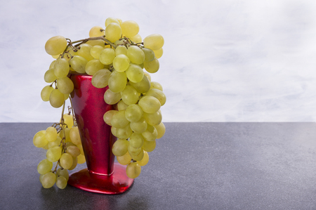 Grapes is sweet and yellow friut on the red vaseの写真素材