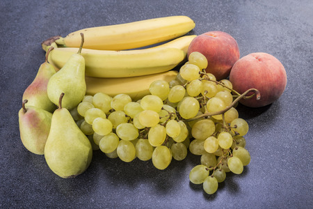 Fruit on top of the kitchen table grapes peaches bananas and pearsの写真素材