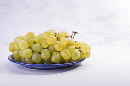 The plate is full of sweet yellow grapes on the white backgroundの写真素材