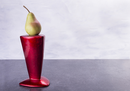 Fruit pear sit on the top of the red vaseの写真素材