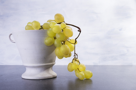 Fruit grapes in the ceramic pot on the tableの写真素材