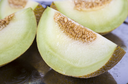 Fresh yellow cantaloupe cut in quarter on the old tray in  detailの写真素材