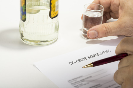 Unhappy man drinking spirit beacuse reading divorce agreementの写真素材