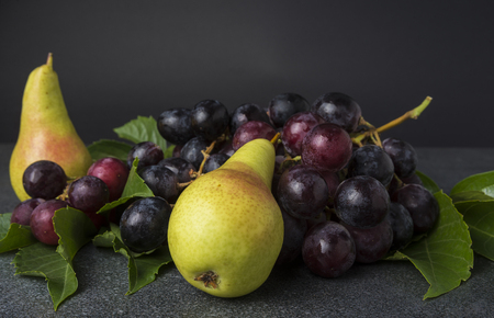 Two pears and cluster of black grapes on the kitchen topの写真素材