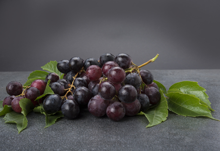 Black grapes cluster with leaves on gray kitchen topの写真素材