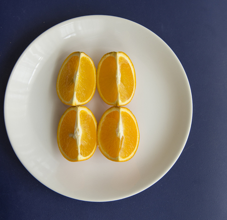 Orange cut in to slices on the white plateの写真素材