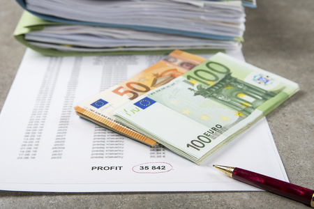 Profit and loss concept image of a pen, calculator and coins on financial documents.の写真素材