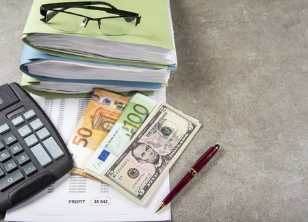 Profit and loss concept image of a pen, calculator and coins on financial documents.の写真素材