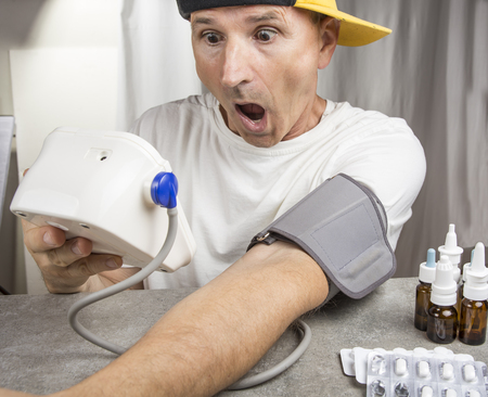 Hypertension concept. Man is measuring blood pressure while he is sickの写真素材