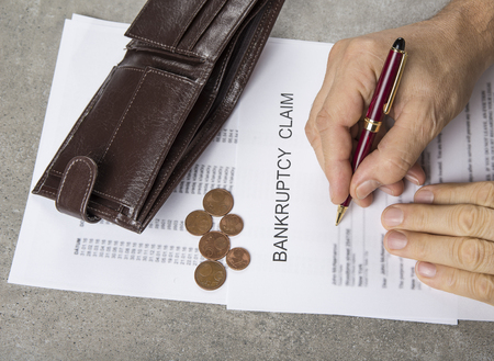 Bankruptcy concept image of a pen, calculator and coins on financial documents.の写真素材