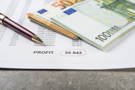 Profit and loss concept image of a pen, calculator and coins on financial documents.の写真素材