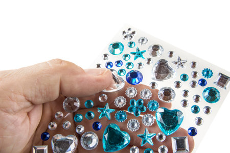 Sticky decoration man made gems in the hand on white
