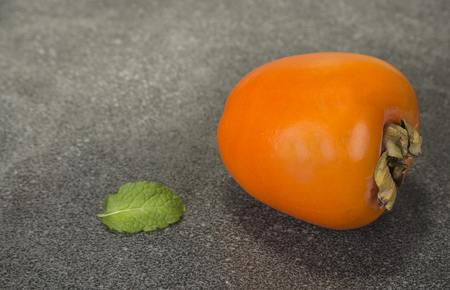 Persimmon fruit on kitchen table with mint leaf.の写真素材