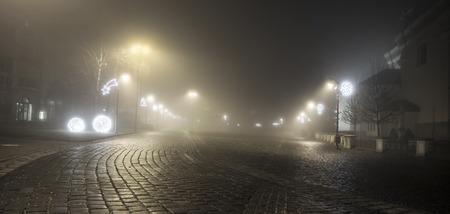 Town in the night in fog with christmas decorationの写真素材