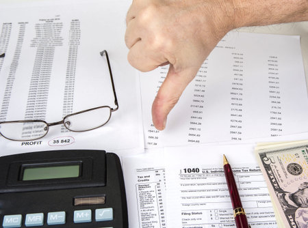 Calculating numbers for income tax return with pen, glasses and calculator