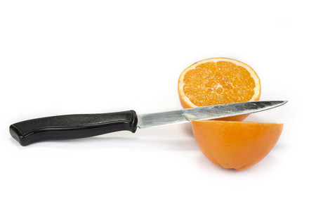 Cut orange on two  halves with kitchen knife on the whiteの写真素材