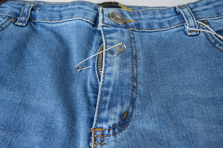 Broken blue jeans zipper fixed with safety pinの写真素材