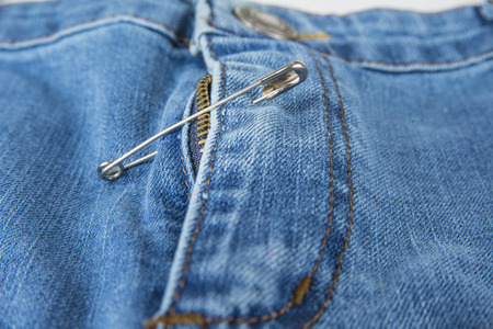 Broken blue jeans zipper fixed with safety pinの写真素材