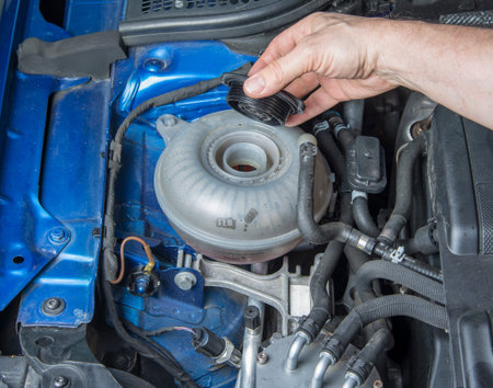 Man is opening car radiator fluid tank to check  the level