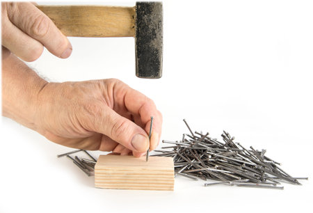 Man is hammering the nail on the white