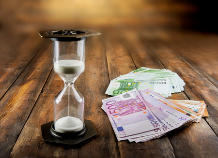Hourglass on a wooden background. Time is money concept