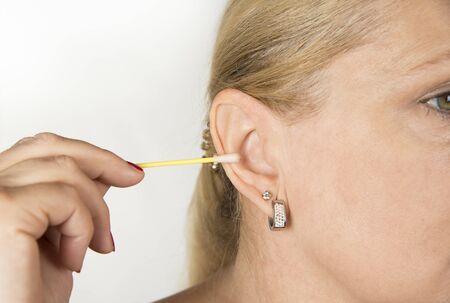 Woman cleaning her ear with a swabの写真素材