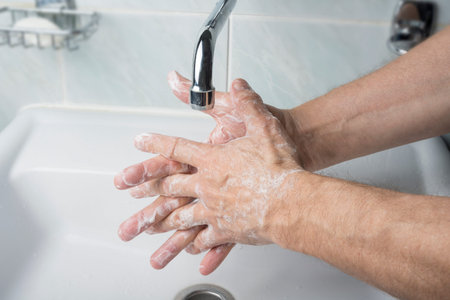Older male is washing his hand under faucet