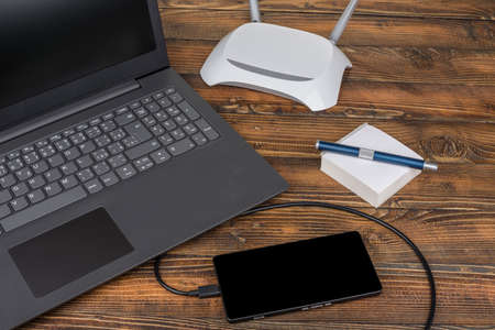 Modern laptop smartphone wih a usb cable on a woodの写真素材