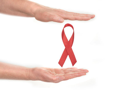 Breast cancer symbol between hands on a white background