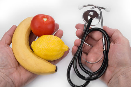 Healthy lifestyle and fruit versus stethoscope in the handsの写真素材