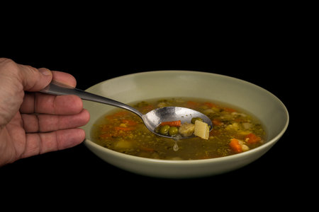 Spoon  and vegetable soup on a black backgroundの写真素材
